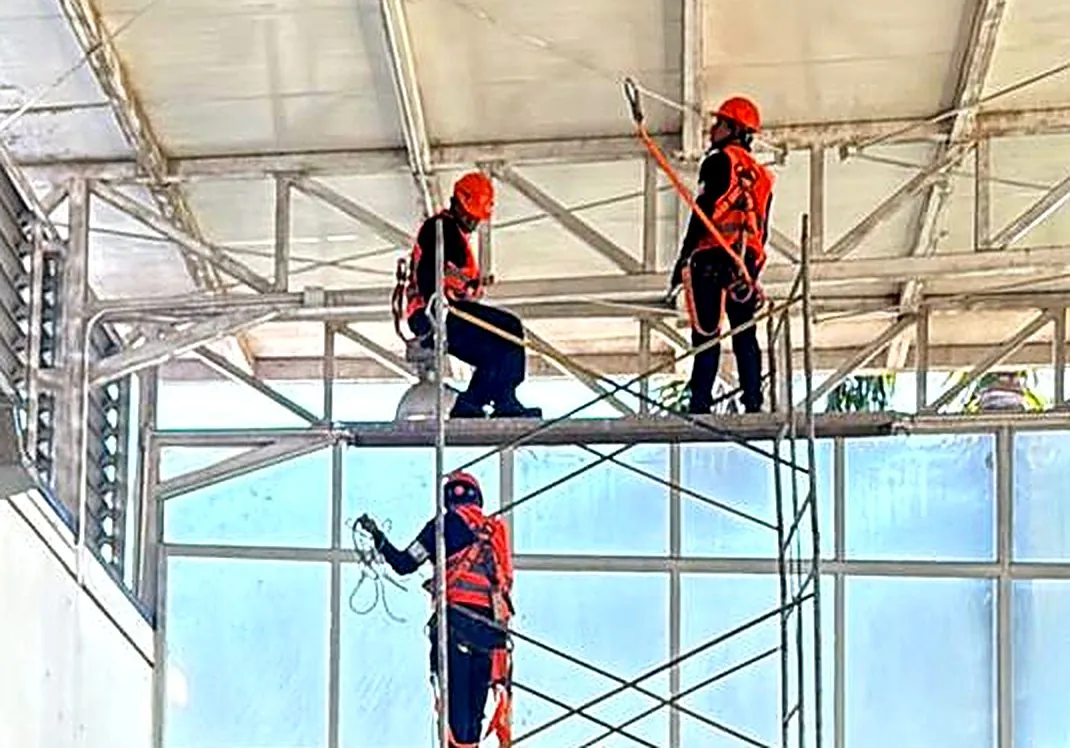 Personal con arnés y línea de vida trabajando desde andamio en la cara interior de la cubierta del aeropuerto de Florencia